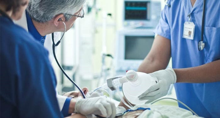 Doctor listening to patients heart beat while a nurse is providing oxygen